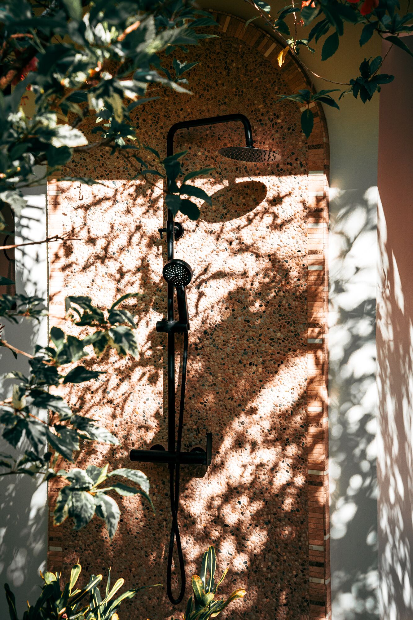 Outdoor shower beneath a dappled stone arch