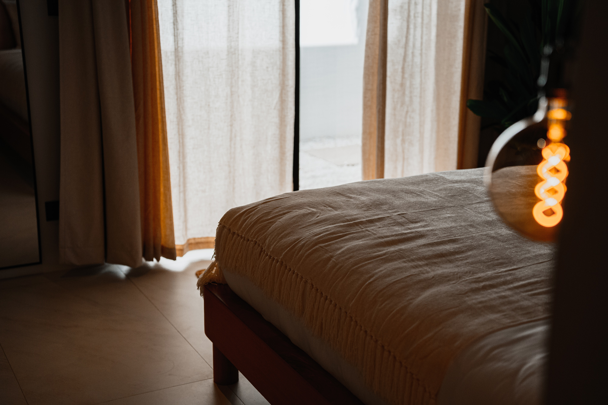 Serena villa bedroom with linen and edison bulb bokeh